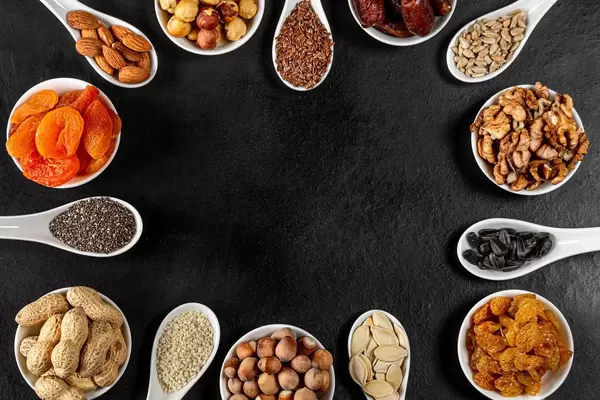 Frame of nuts, dried fruits and seeds on a black background with free space (Flip 2020)