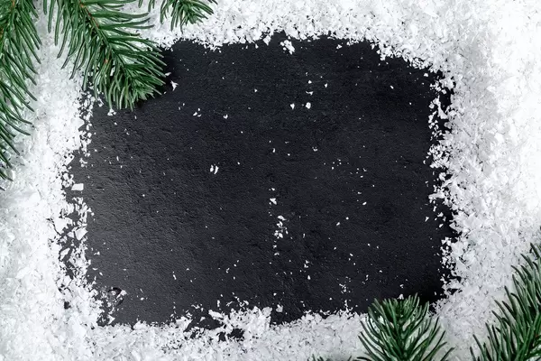Frame of snow and Christmas tree branches on a black background