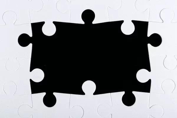 Frame of white puzzles on a black background with free space