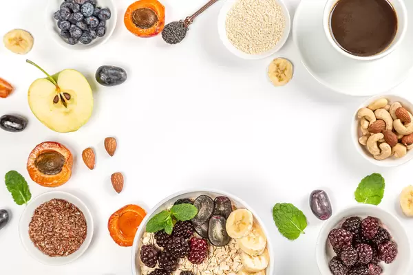 Frame with coffee, oatmeal, fruit, nuts and seeds on white with free space, top view