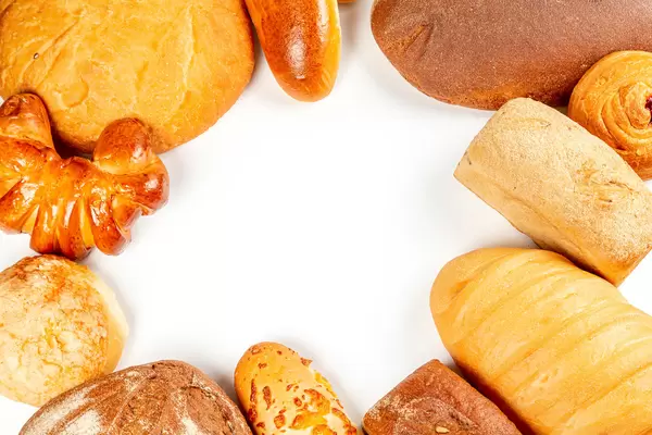 Frame with different types of bread, buns and pies on a white background, top view with free space