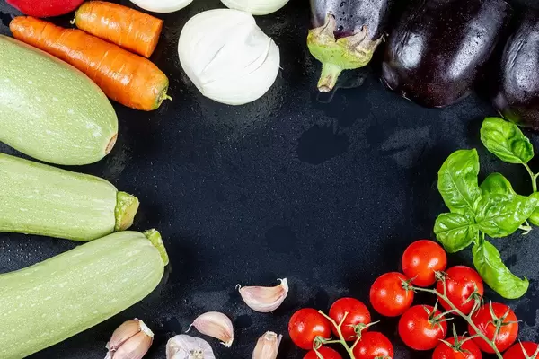 Frame with fresh vegetables with water drops on a black background, top view
