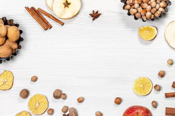 Frame with nuts spices dried citrus and fresh slices apple on a white wooden background. The view from the top (Flip 2019)