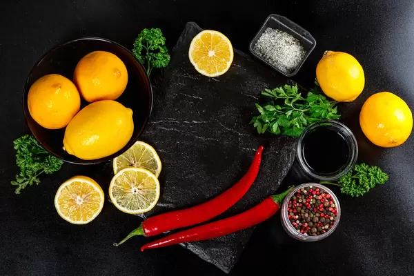 Frame with spices, lemon and herbs on a dark background, top view