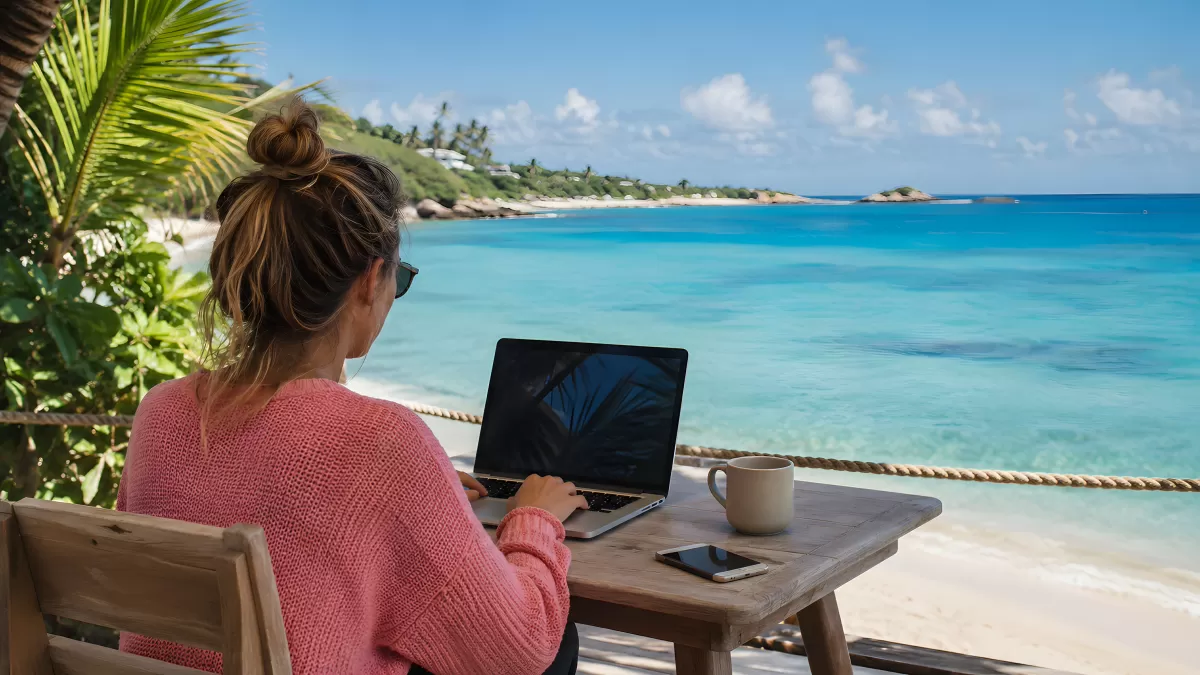 Frau arbeitet am Laptop mit Meerblick am Strand