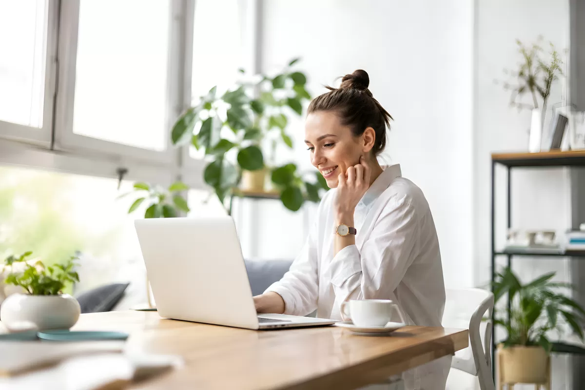 Frau arbeitet lächelnd am Laptop im Homeoffice