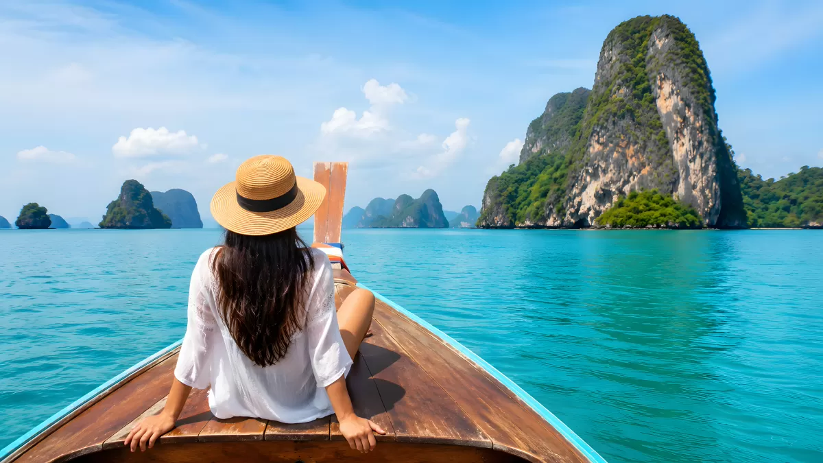 Frau auf Longtailboot zwischen Kalksteinfelsen in Thailand