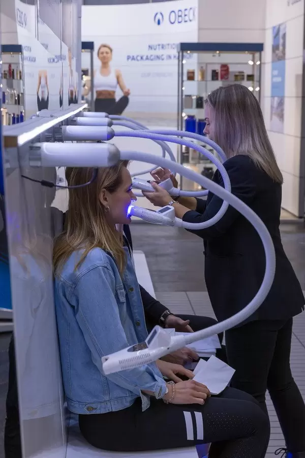 Frau beim Zahnbleaching mit der Sunshine Smile Aparatur auf der Messe Fibo in Köln