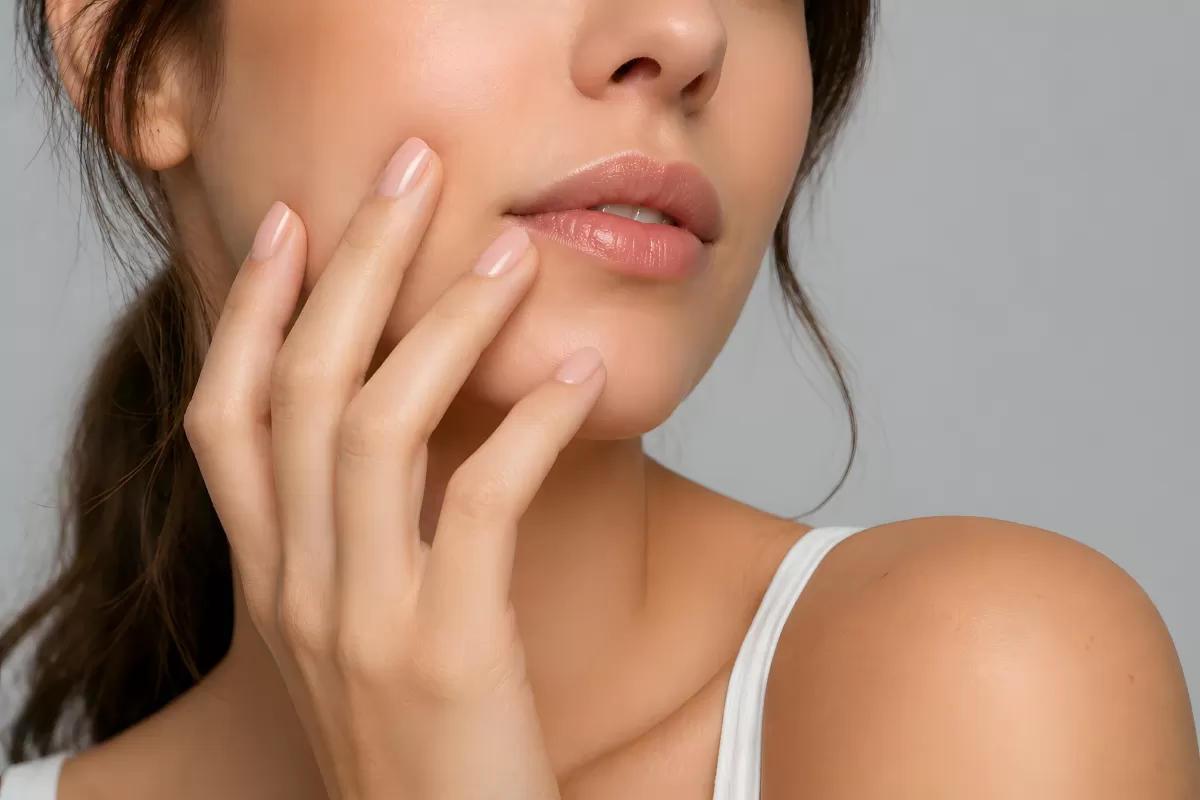 Frau berührt sanft ihr Gesicht mit gepflegter Hand