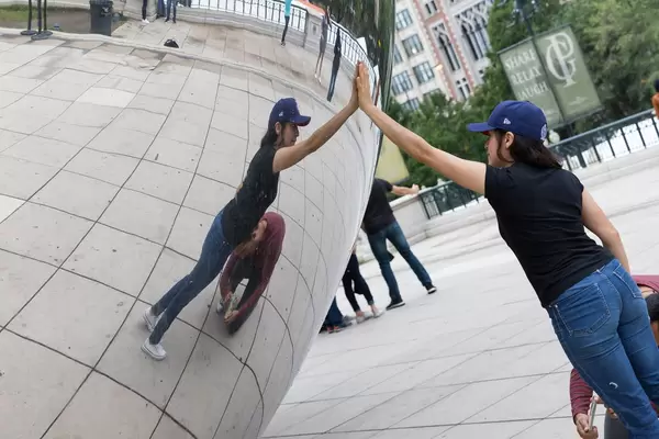 Frau berührt die Skulptur Cloud Gate