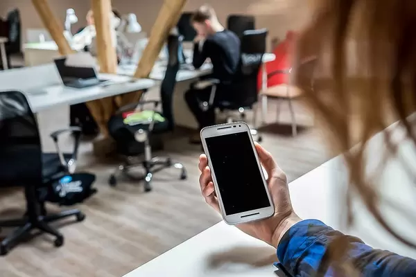 Frau blickt im Büro auf ihr Smartphone