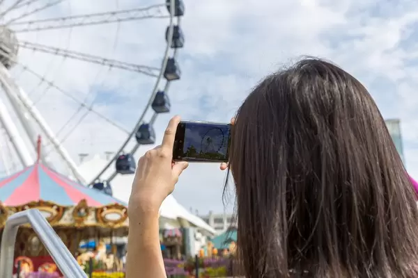 Frau fotografiert mit ihrem Smartphone das Riesenrad an der Seebrücke "Navy Pier" am Michigansee