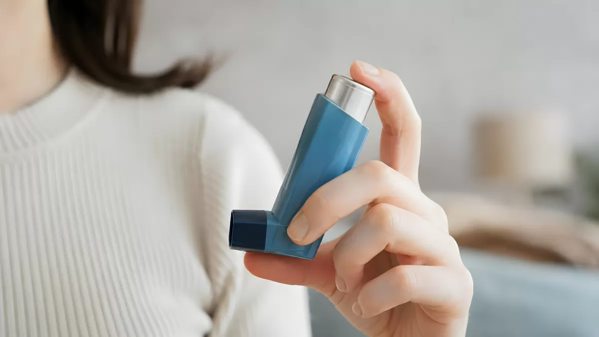 Frau hält blauen Asthma-Inhalator in der Hand