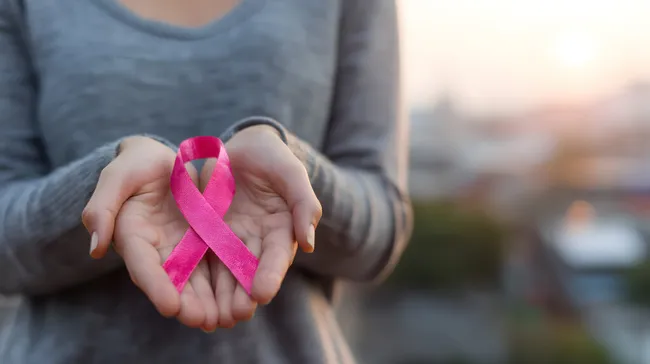 Frau hält pink-roten Krebs-Bewusstseinsband