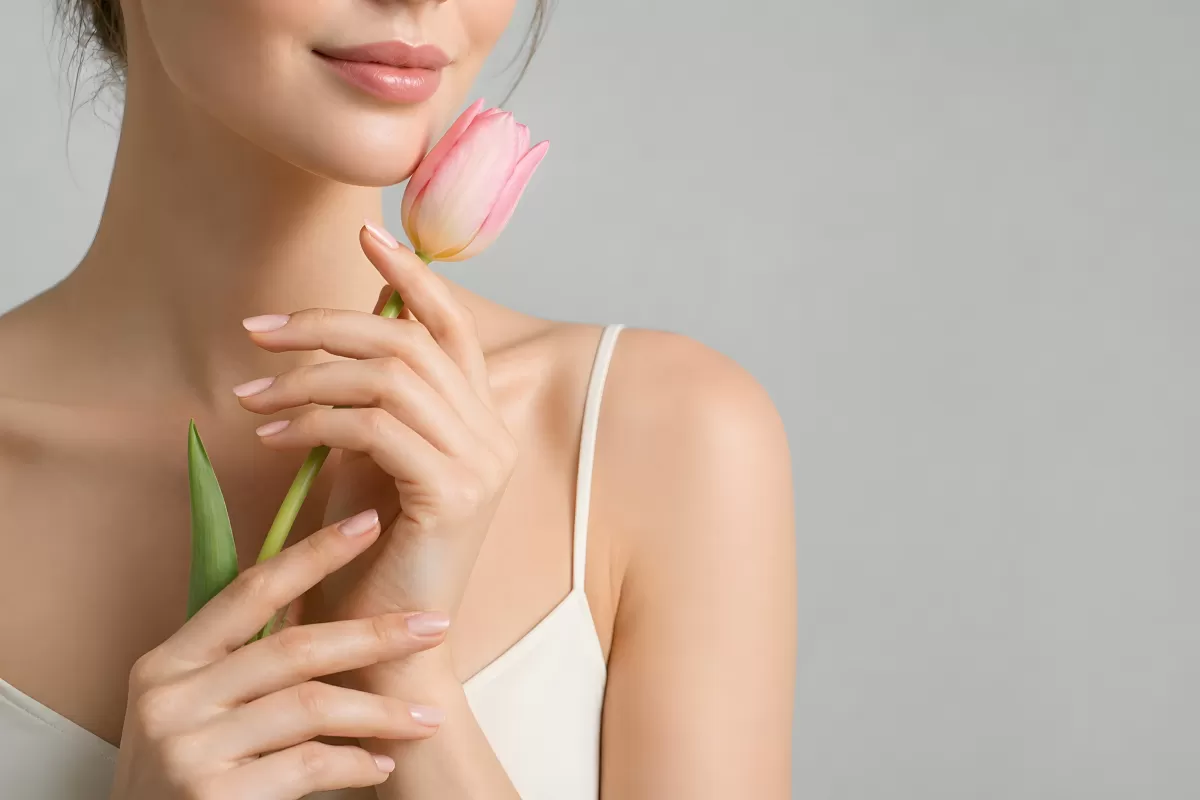 Frau hält rosa Tulpe sanft ans Gesicht im Frühling