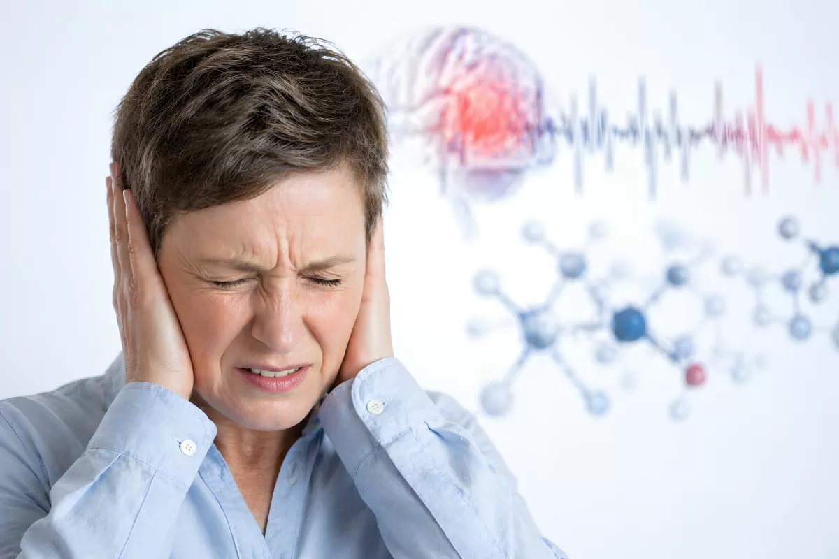 Frau hält sich Ohren zu bei starken Kopfschmerzen
