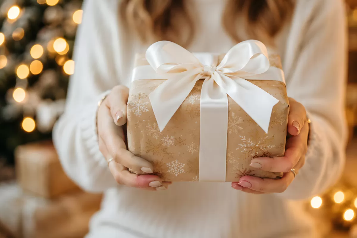 Frau hält Weihnachtsgeschenk mit weißer Schleife