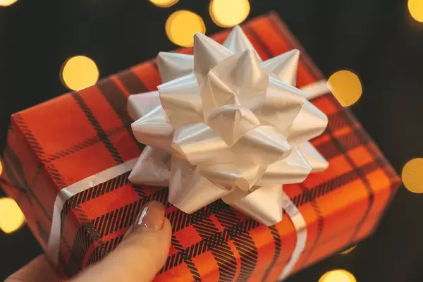 Frau hält ein Weihnachtsgeschenk mit weißer Schleife in der Hand