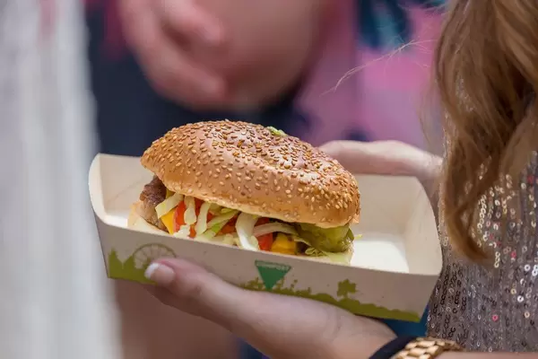 Frau hält Hamburger auf einem kompostbaren Papierteller in ihrem Hand auf dem Tomorrowland Festival