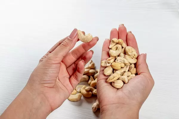 Frau hält rohe Cashewnüsse in den Händen als Symbol der gesunden Ernährung