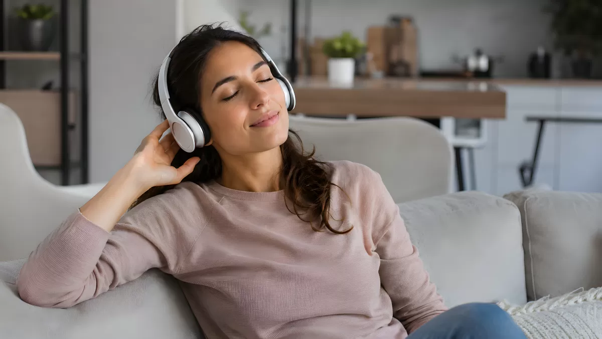 Frau hört Musik mit Kopfhörern auf dem Sofa