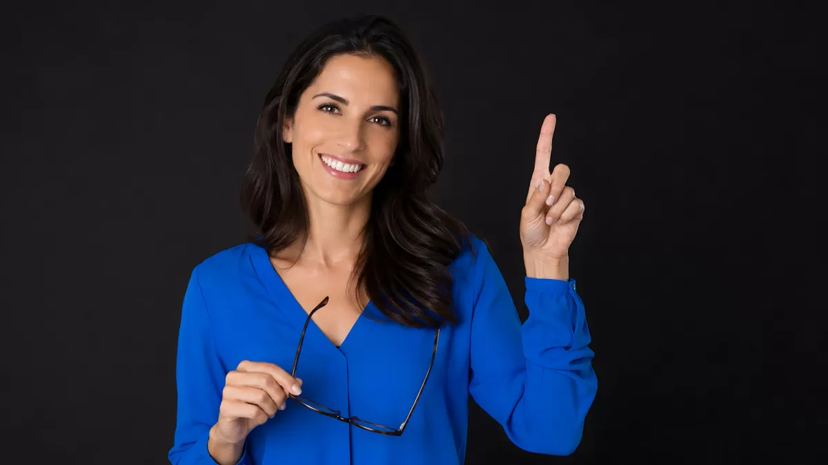 Frau im blauen Blazer zeigt Idee mit erhobenem Finger