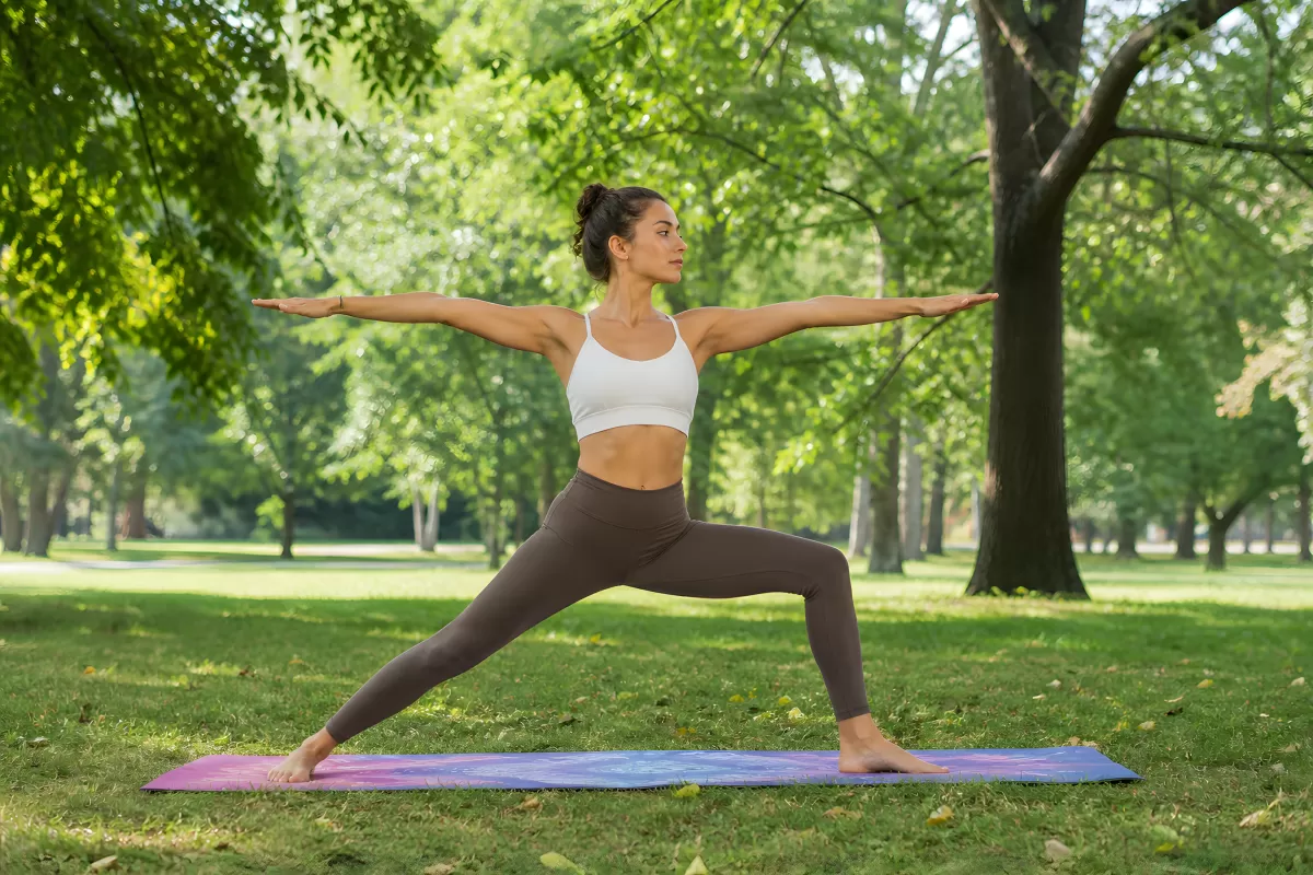 Frau in Krieger-Pose beim Yoga im grünen Park