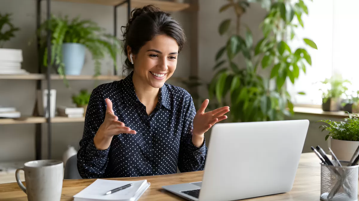 Frau lächelt beim Videogespräch am Laptop im Homeoffice