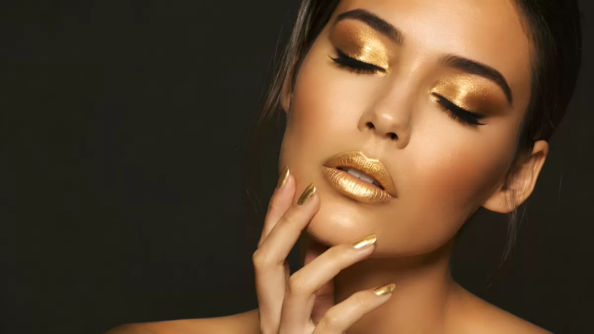 Frau mit goldenem Make-up und Nagellack in Studioaufnahme