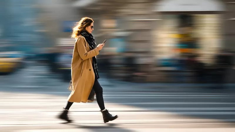 Frau mit Smartphone läuft durch Stadt in Bewegung