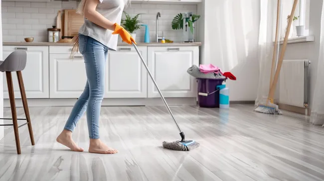 Frau reinigt mit Mopp und Eimer moderne Küche