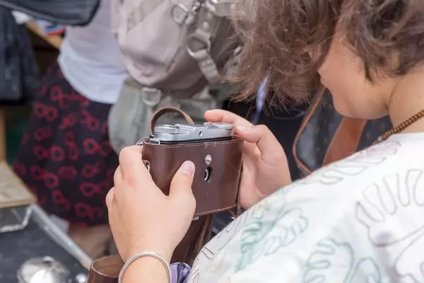 Frau schaut sich gebrauchte Kameras am Naschmarkt Flohmarkt an
