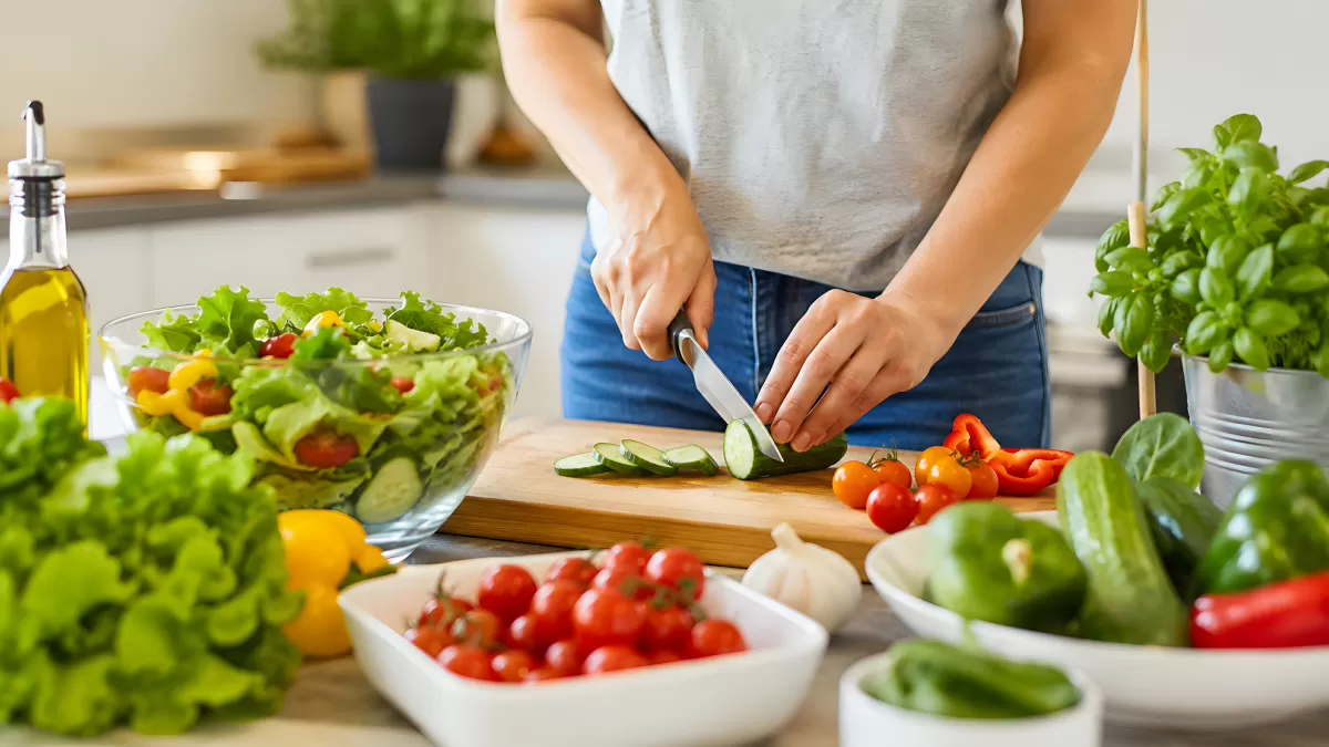 Frau schneidet Gurke für bunten Gemüsesalat