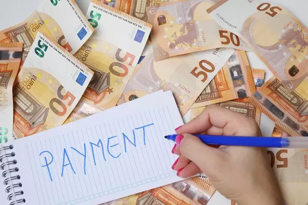 Frau schreiben "Payment / Zahlung" auf einen Zettel zwischen 50-Euro-Geldscheinen