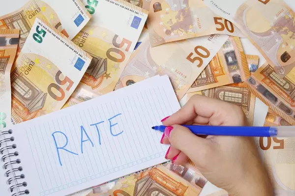 Frau schreiben "rate / Bewertung" auf einen Zettel zwischen 50-Euro-Geldscheinen