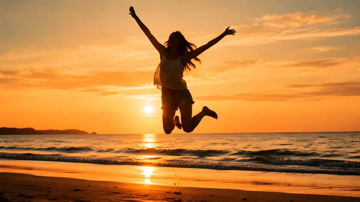 Frau springt freudig am Strand beim Sonnenuntergang