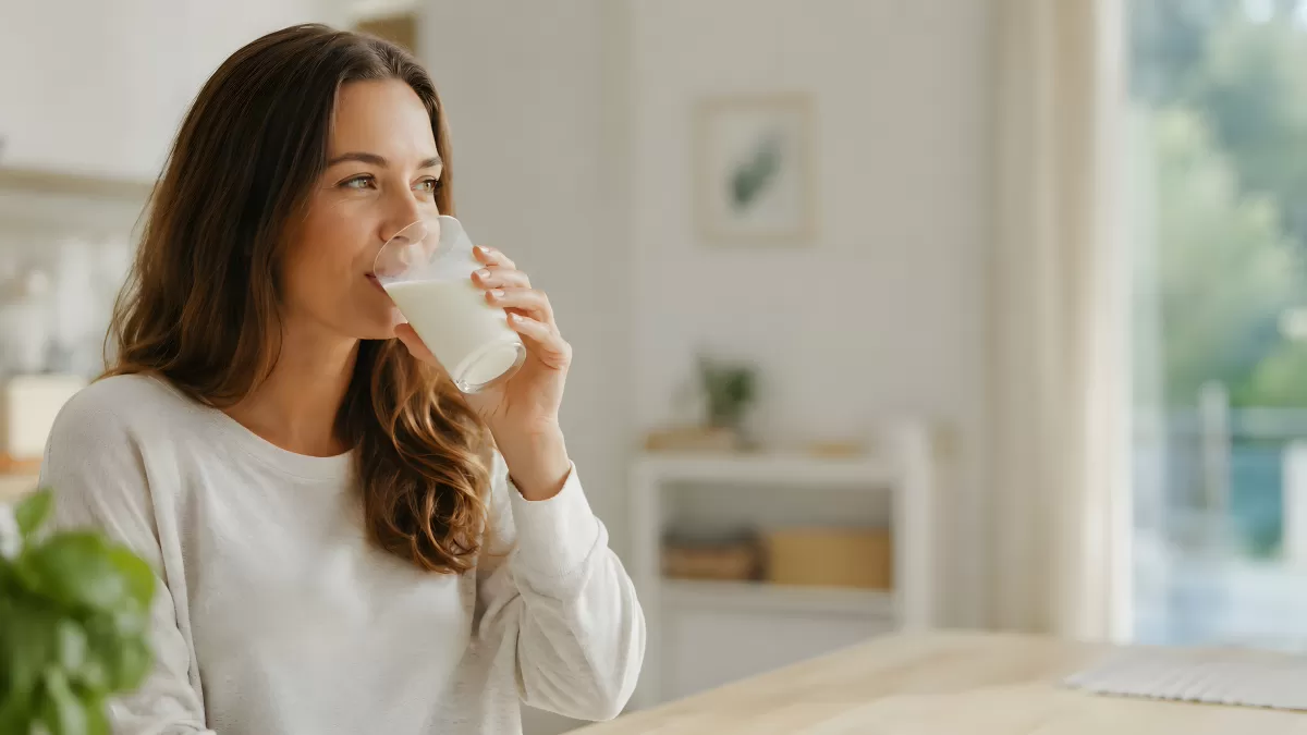 Frau trinkt ein Glas Milch in heller Küche