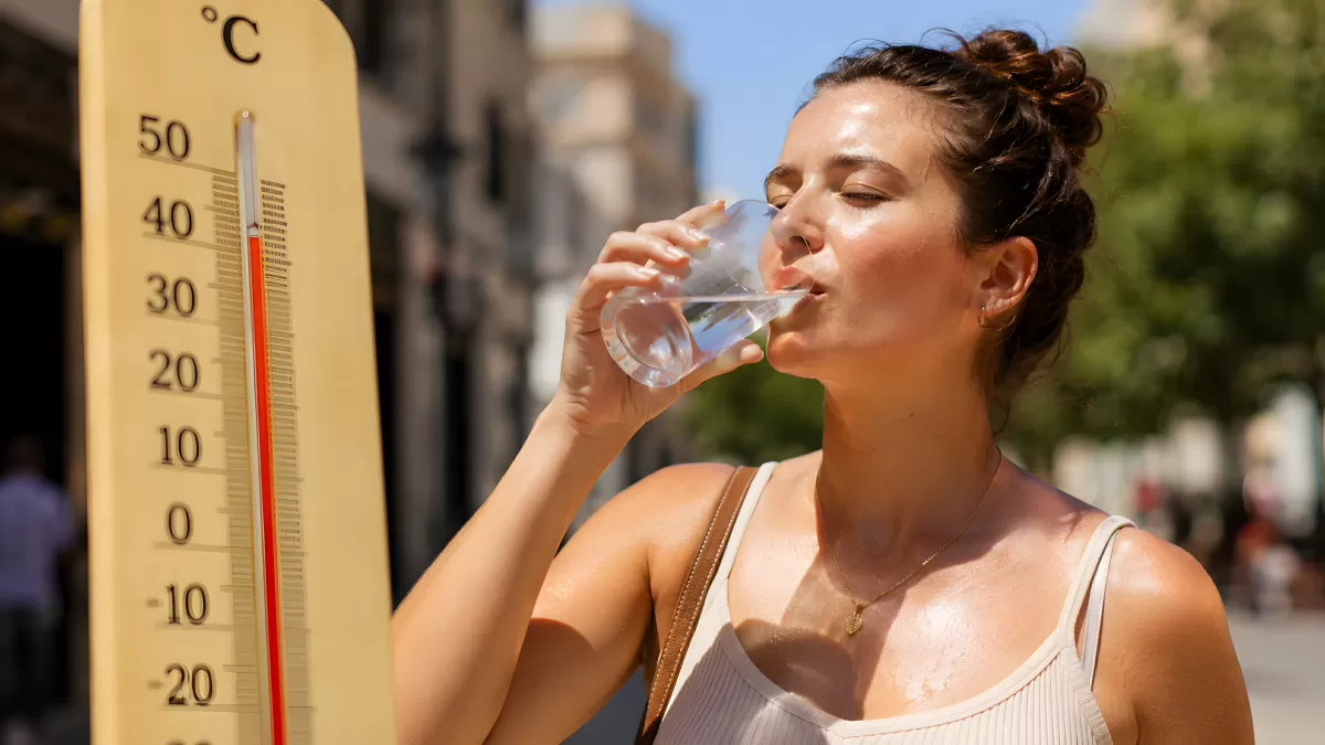 Frau trinkt Wasser bei extremer Hitze im Sommer