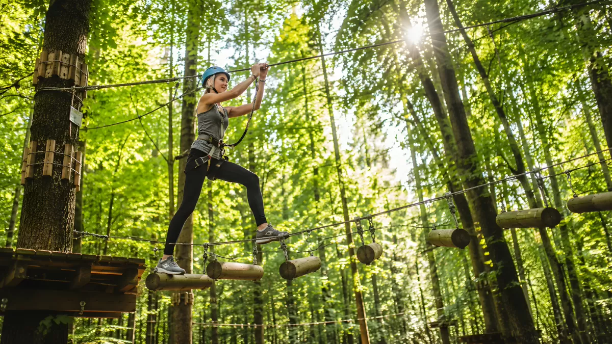 Frau überquert Hängebrücke im Kletterpark
