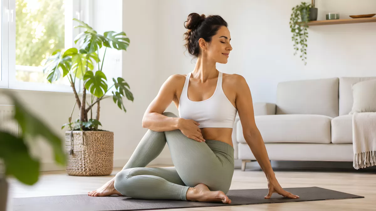 Frau übt Yoga in sonnigem Wohnzimmer