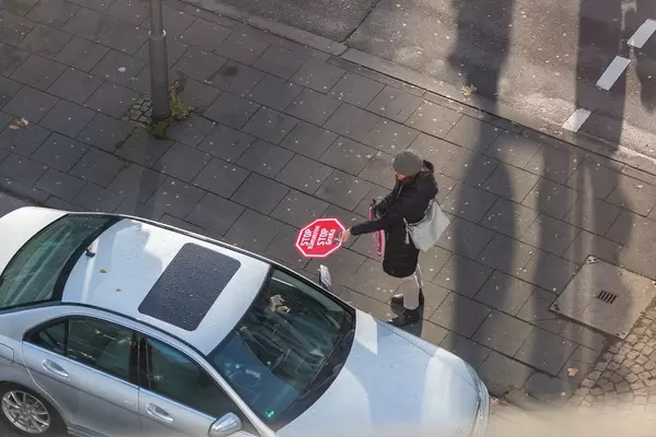 Frau verteilt Stop Klimakrise - Stop GroKo Schilder an Auto Fahrer