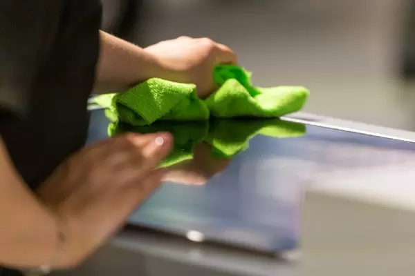 Frau wischt die Küchenarbeitsfläche mit einem trockenen, grünen Lappen