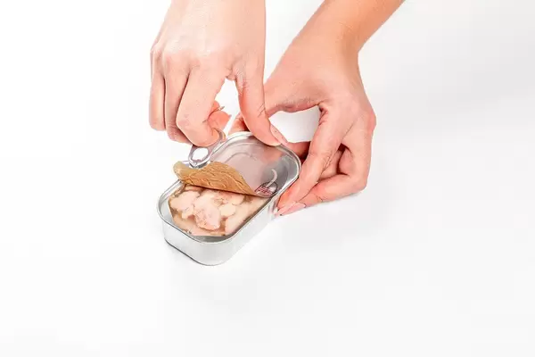 Frauen Hände öffnen eine Konservendose mit Kabeljau Leber