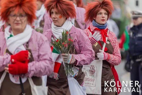 Frauen in Clownskostum verteilen Blumen aus Stofftaschen der Fidelen Zunftbrüder 1919 e.V. beim Kölner Karneval