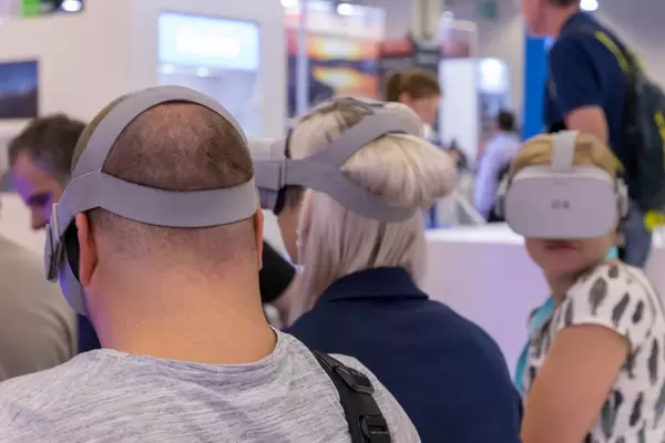 Frauen und ein Mann mit VR Brille an einem Messestand an der Photokina in Köln
