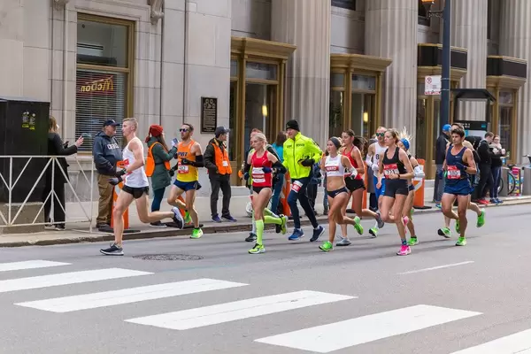 Frauen und Männer nehmen am Chicago Marathon in den USA teil und laufen am Central Standard Building vorbei