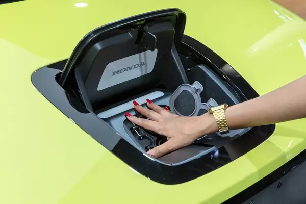 Frauenhand auf der Ladebuchse für CCS2-Stecker, in der Motorhaube des Honda-e Elektrowagens