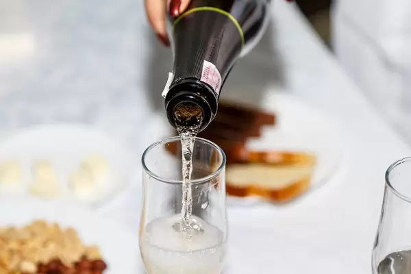 Frauenhand schüttet Schaumwein in ein Glas
