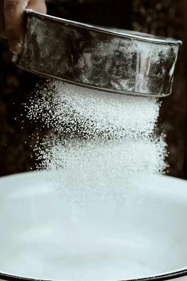 Freezed motion shot of pouring flour on dough for preparing cookies
