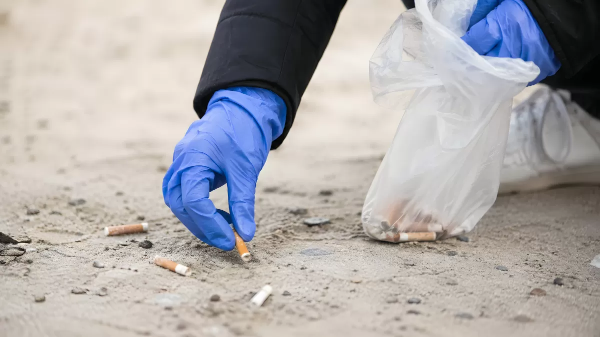 Freiwilliger sammelt Zigarettenstummel am Strand